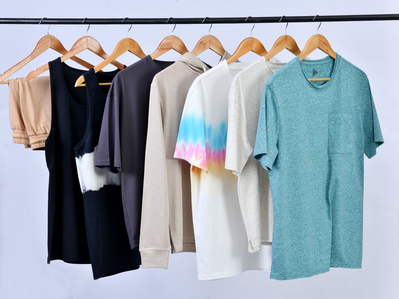 A variety of casual t-shirts on wooden hangers displayed in a minimalist style.