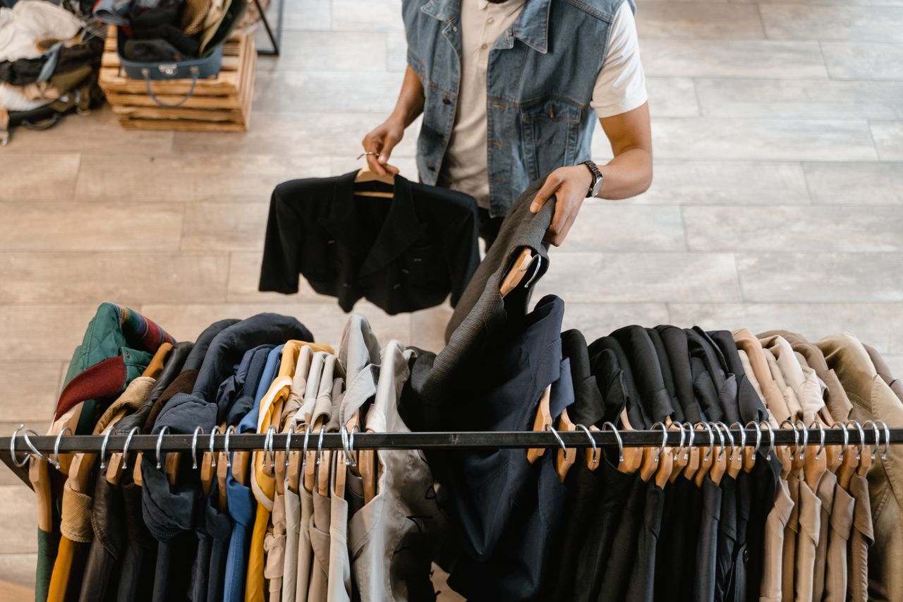 quality-assurance-02 A person holds a jacket while organizing clothes on a rack in a stylish boutique.